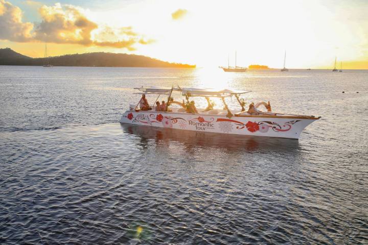 An outrigger canoe sailing in Bora Bora at sunset time