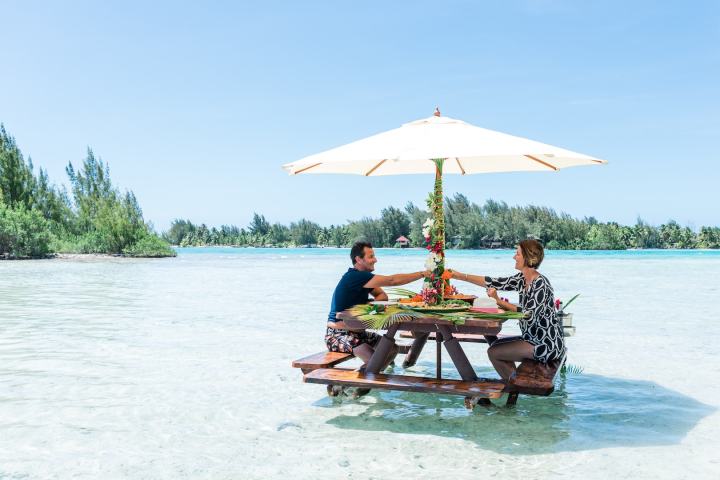 A couple having water lunch with champagne on a private island in Bora Bora