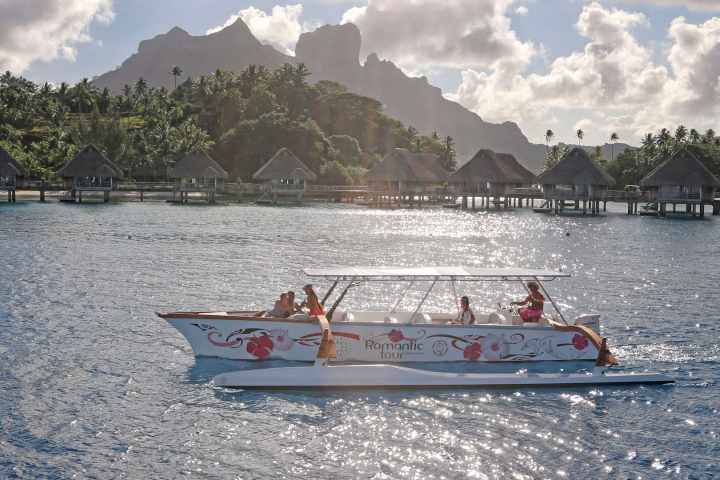 An outrigger canoe sailing in Bora Bora at sunset time