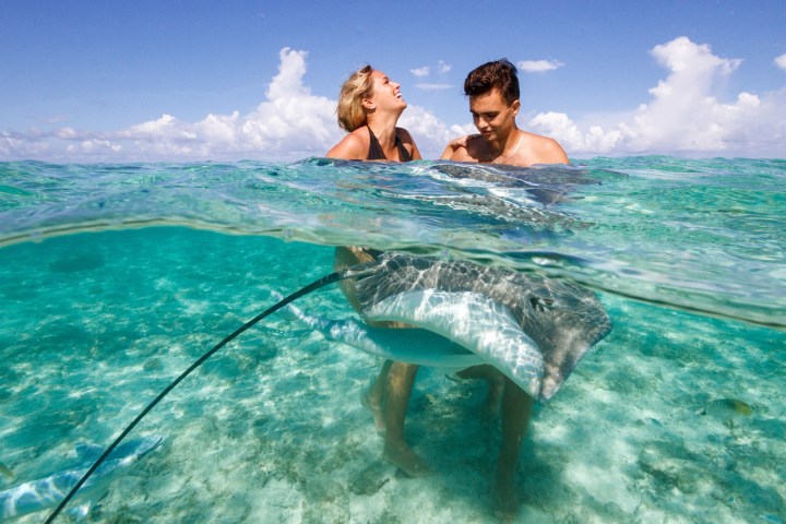 A couple having fun with rays during a boat tour in Bora Bora